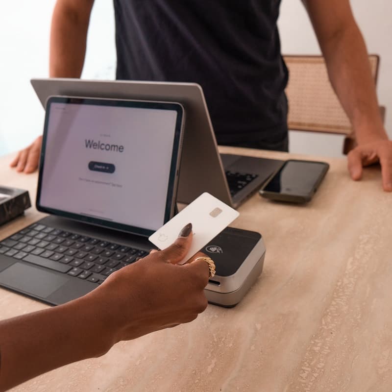 A well-manicured hand holds a credit card as a salon employee prepares to process a payment.