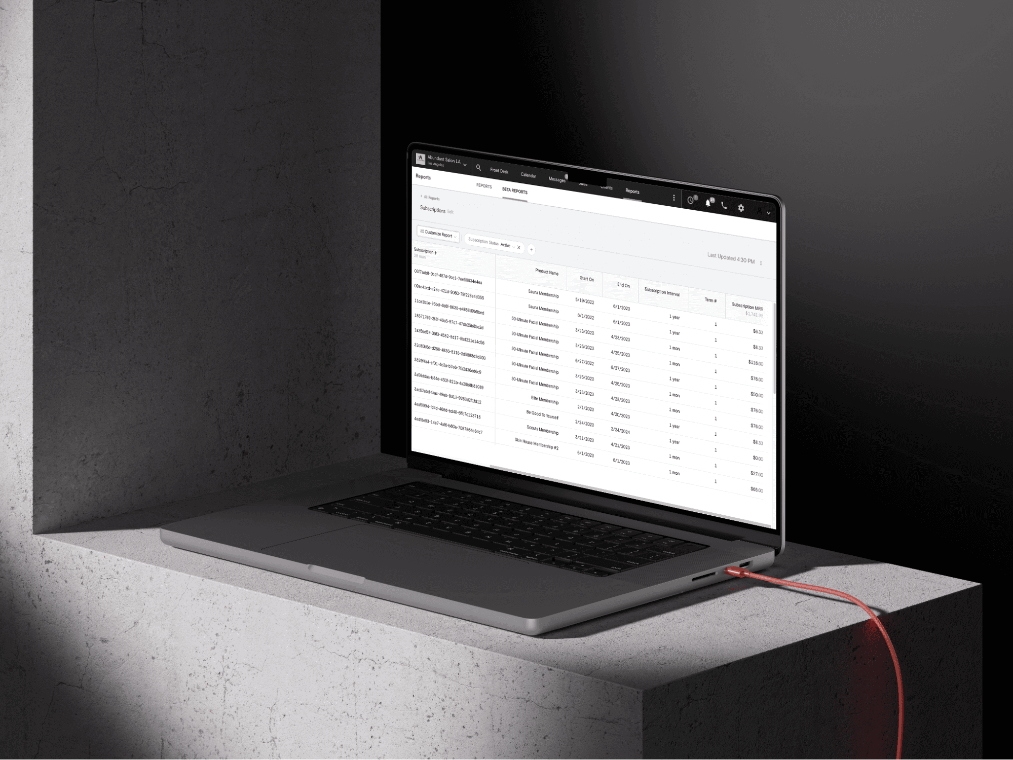 An open laptop sits on a slate table. The screen shows Boulevard's Reporting tools.