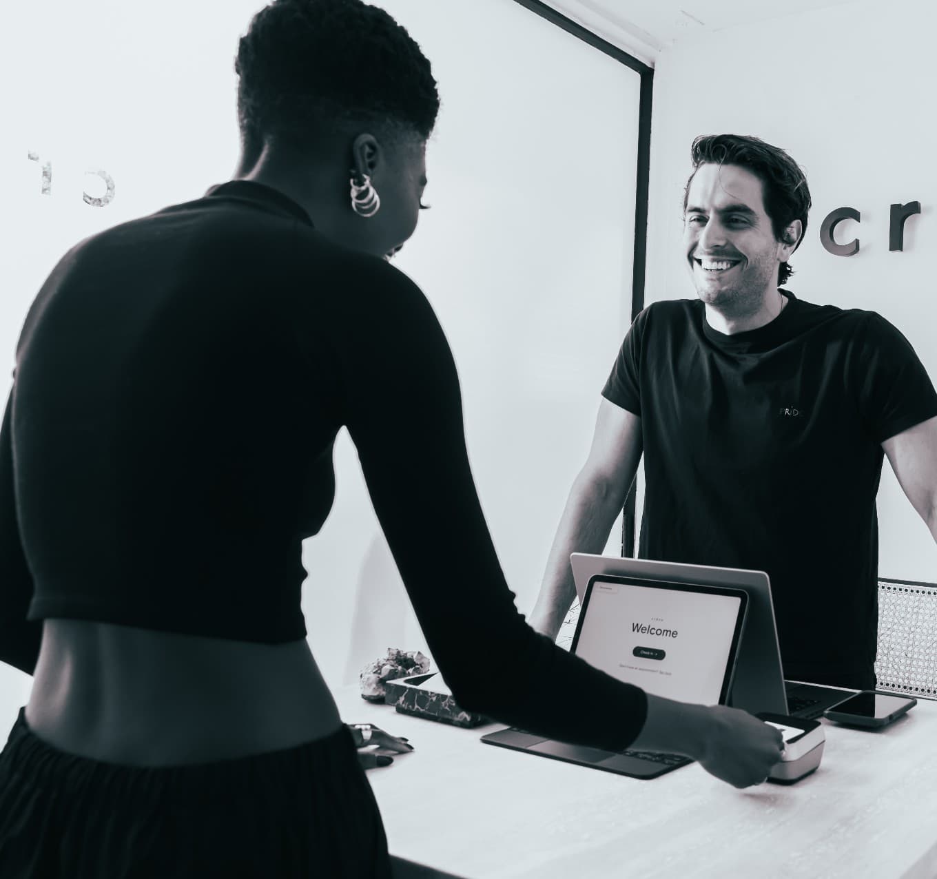 A satisfied customer uses a tablet at a reception desk to complete a transaction. 