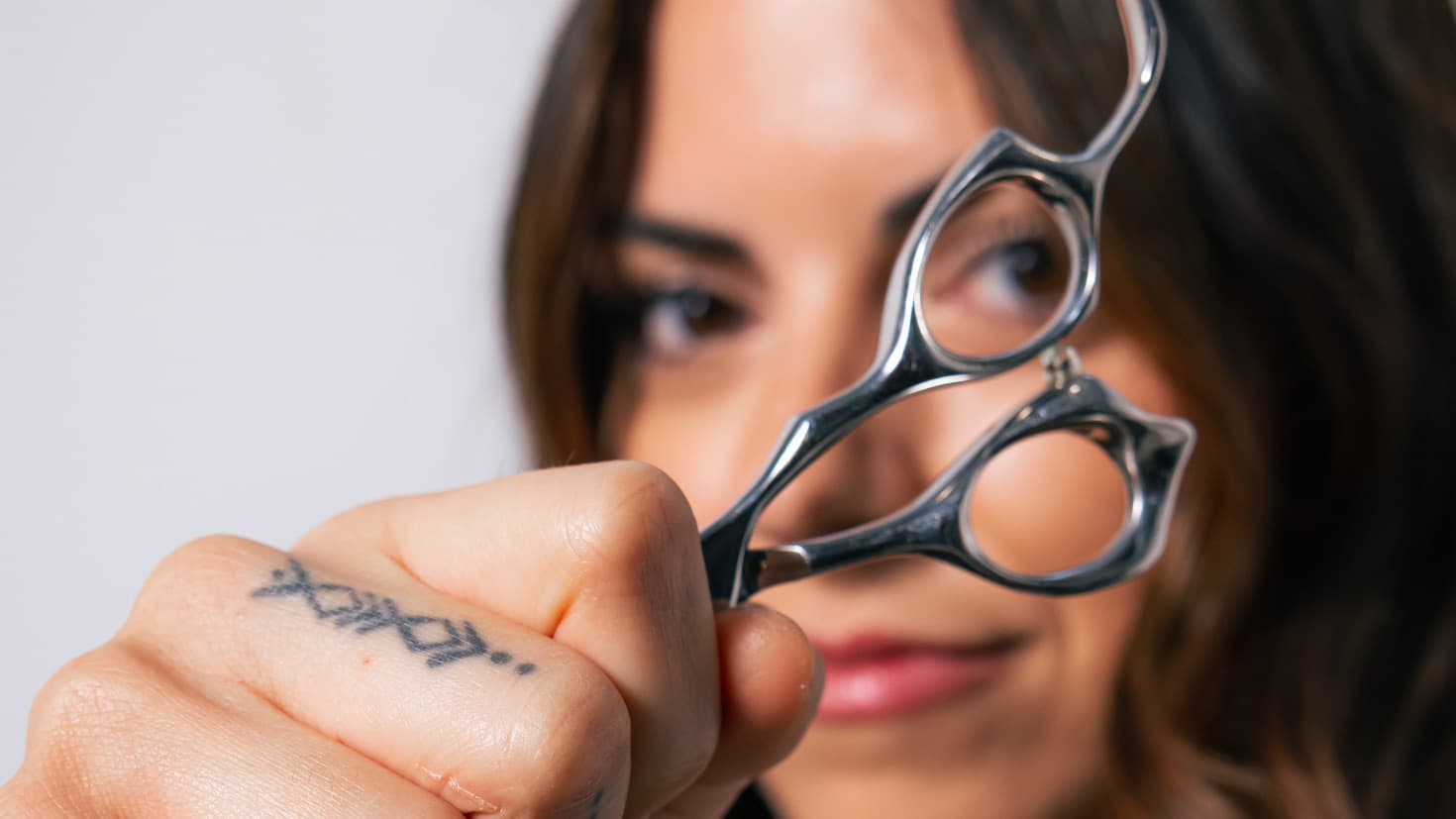 A close up of a woman holding up a pair of scissors in front of her face.