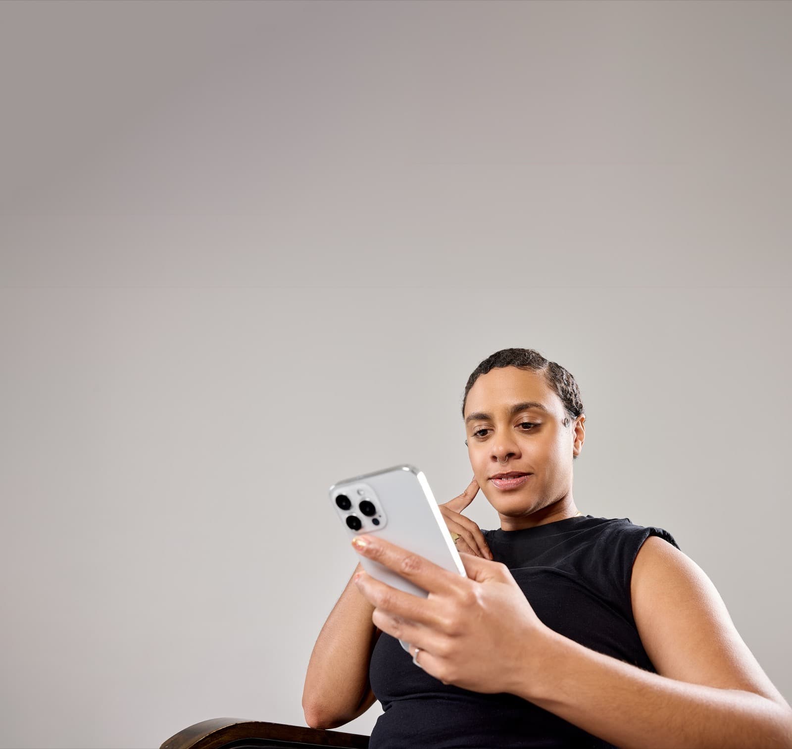 A client sits in a salon chair looking at her phone, reviewing her Buy Now, Pay Later payment options.
