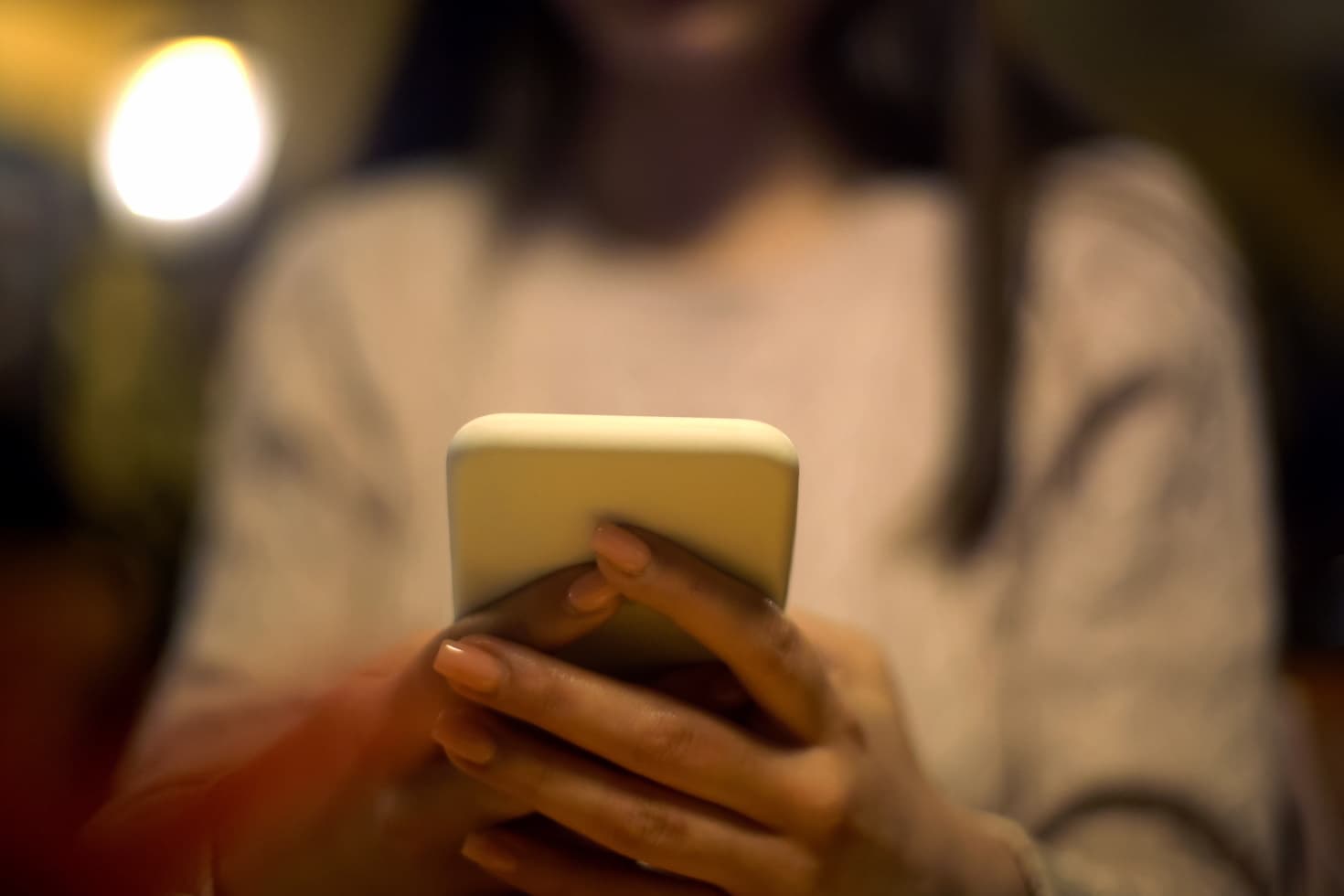 A young woman typing on her smartphone.