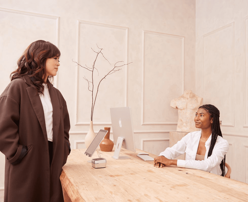 A medspa owner chats with the receptionist at the front desk.