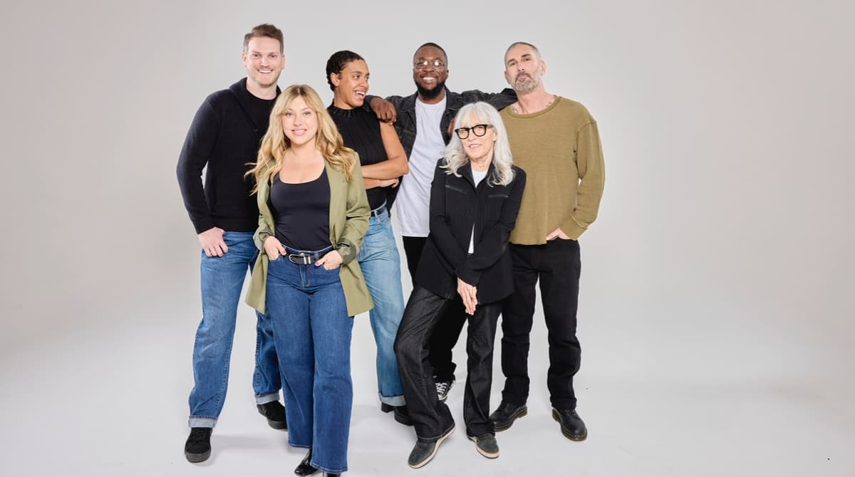 A group of people stand together smiling.