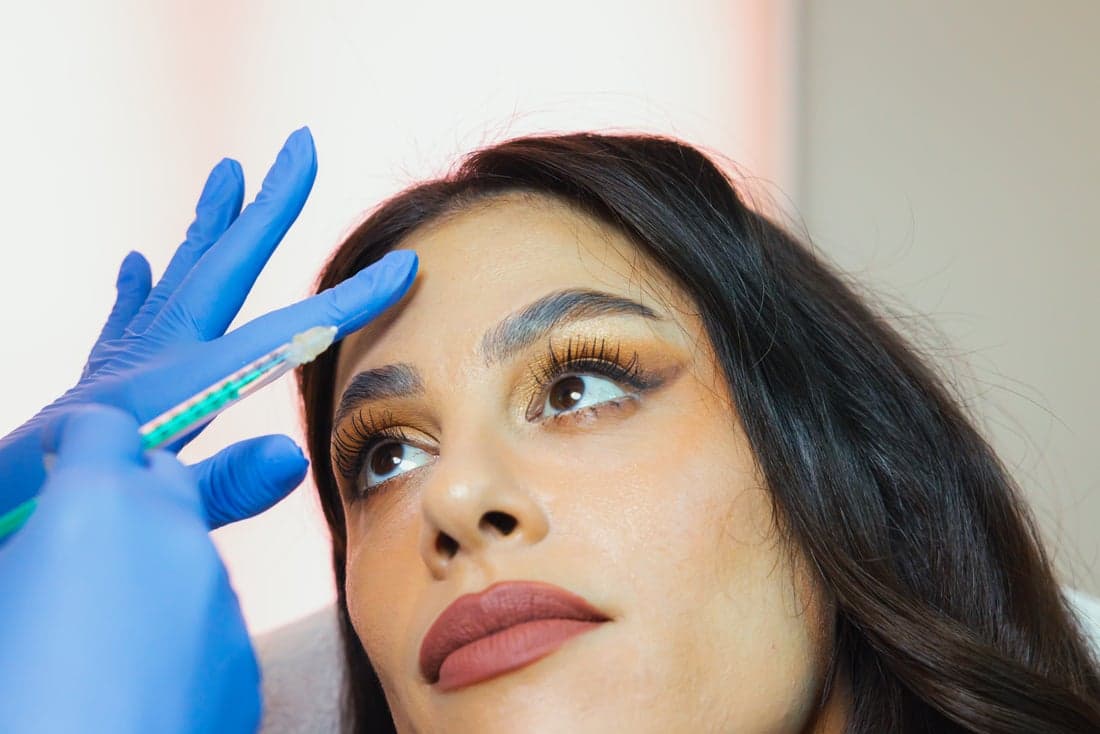 A medspa client prepares to receive a forehead injection